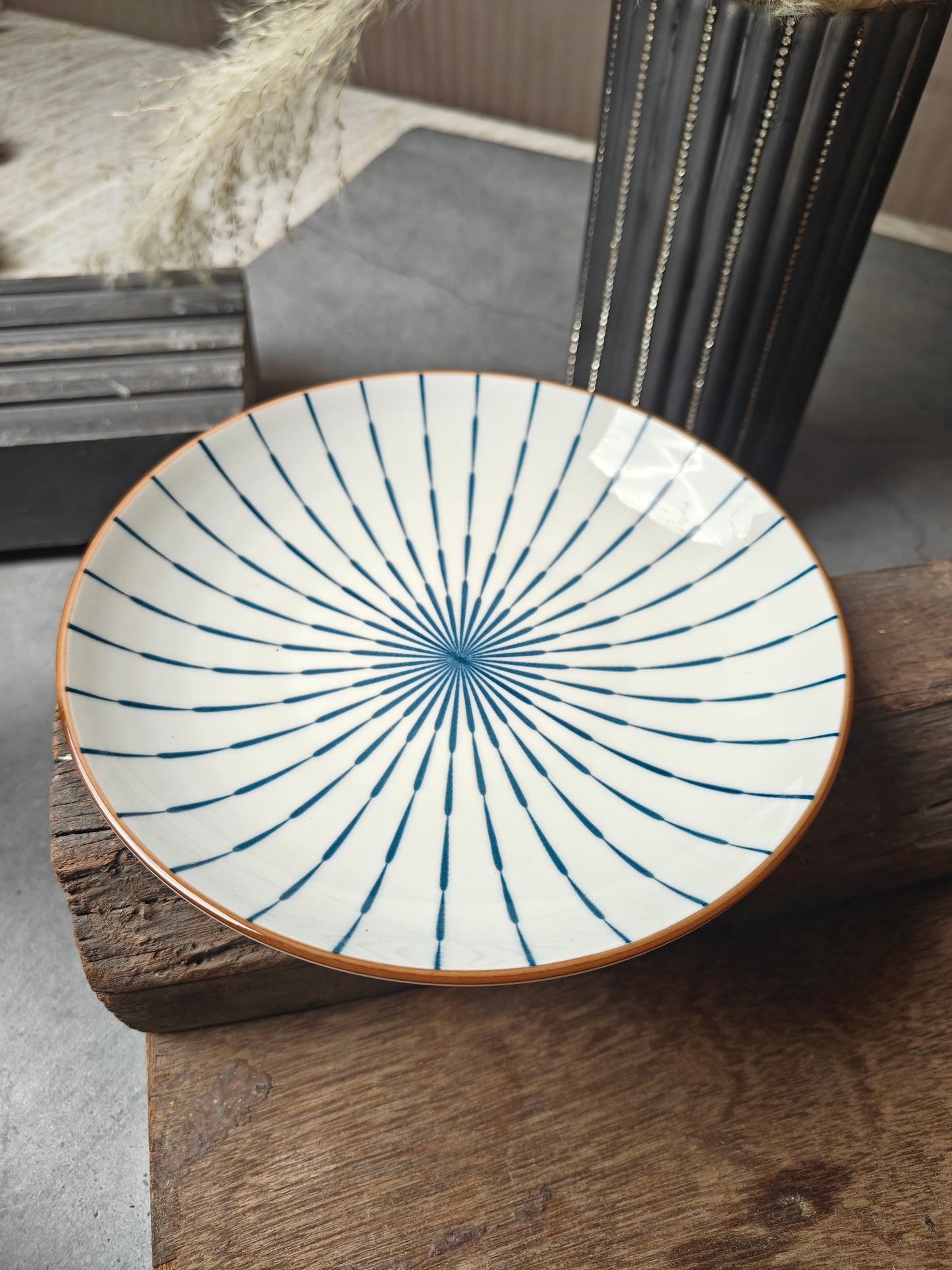 Ceramic sun snack plate with blue radial pattern on a wooden surface