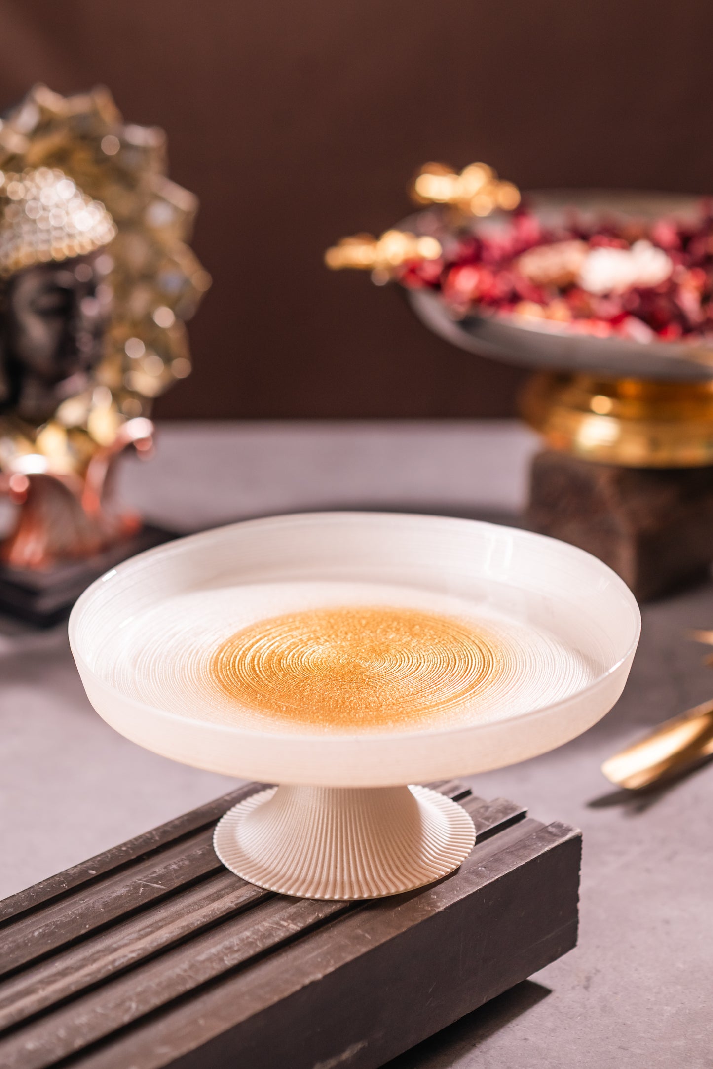 Decorative white bowl with gold interior on a dark surface, blurred background