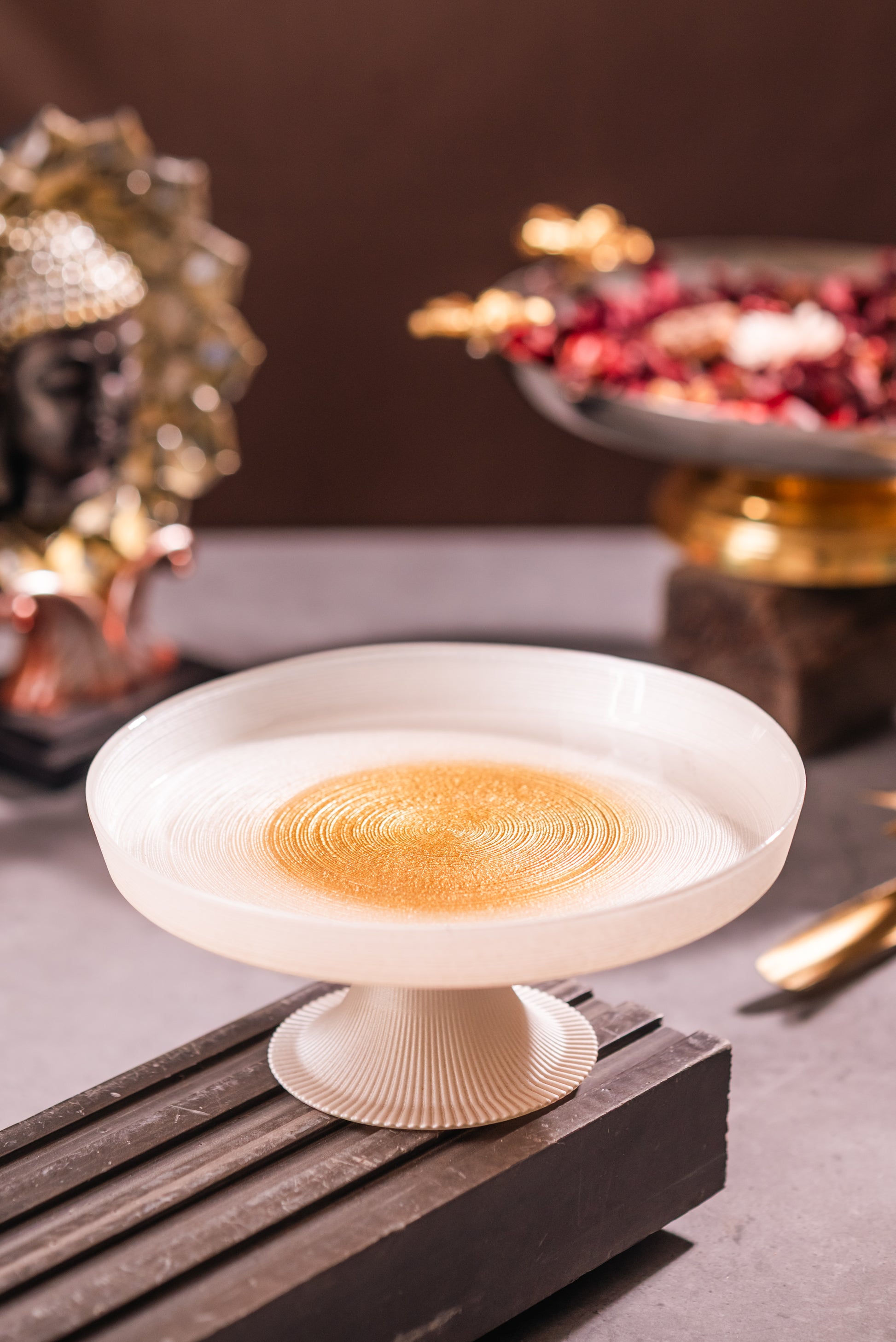 Decorative white bowl with gold interior on a dark surface, blurred background