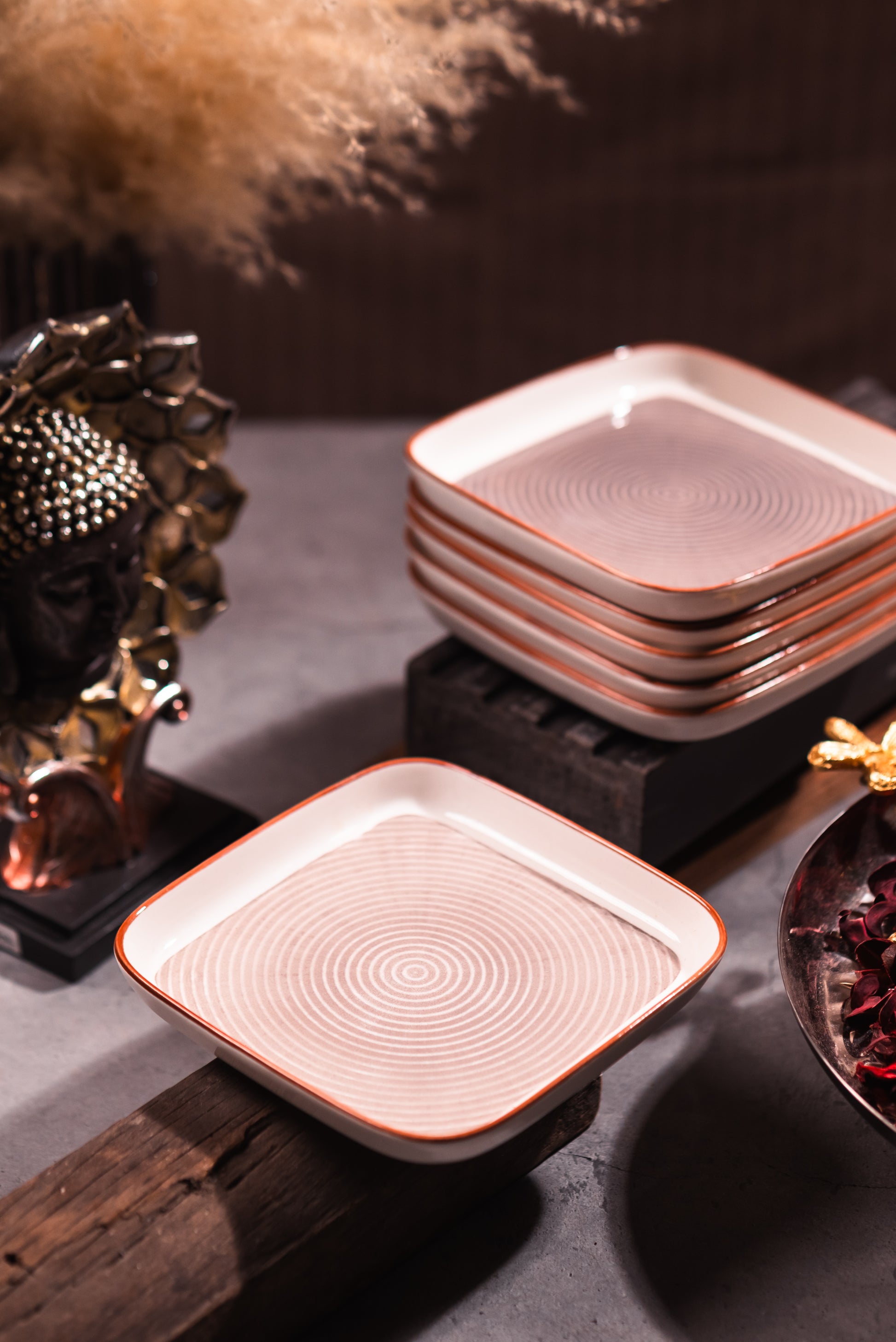 Stack of ceramic plates with decorative patterns on a textured surface