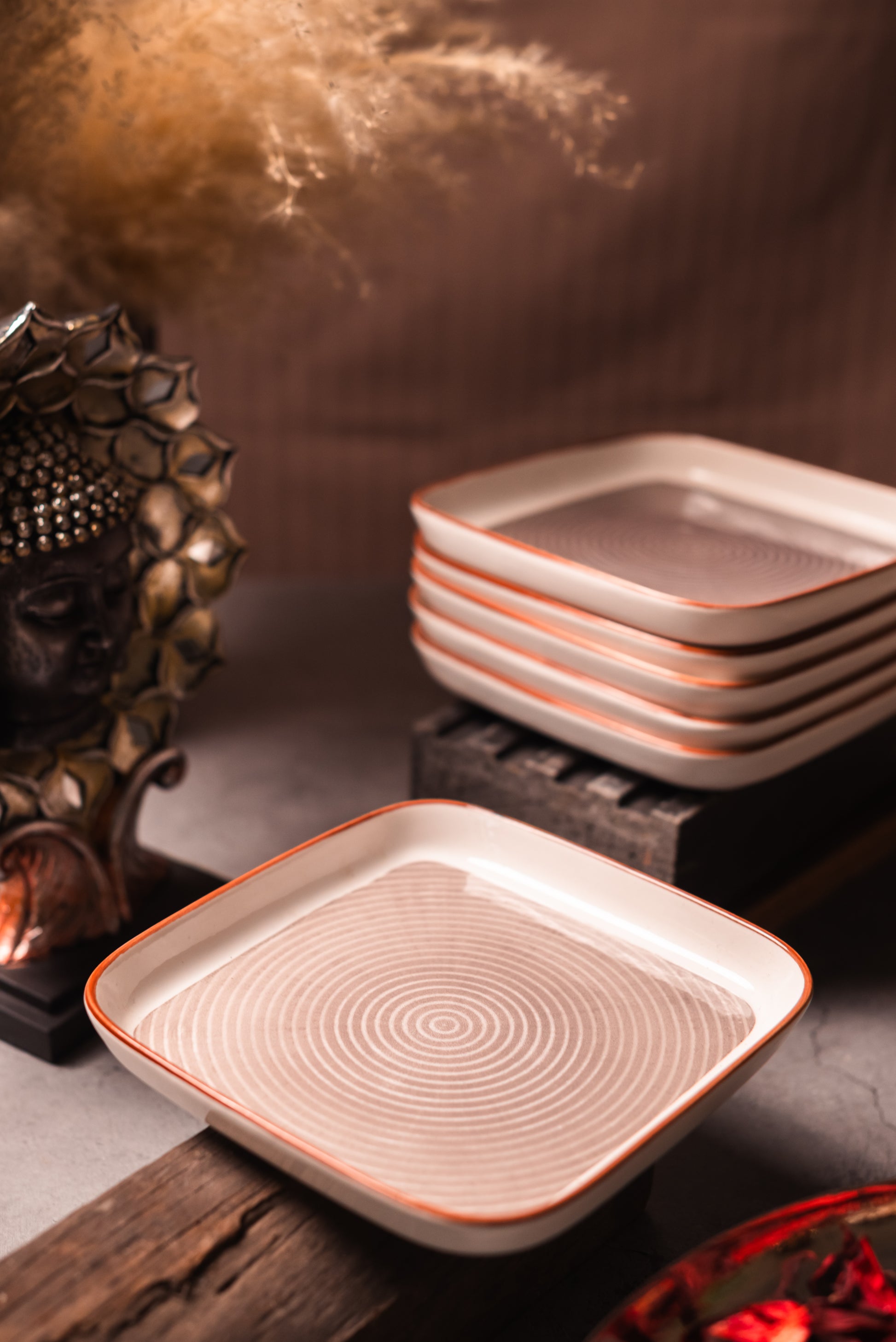 Set of ceramic square snack plates with decorative patterns on a wooden surface.