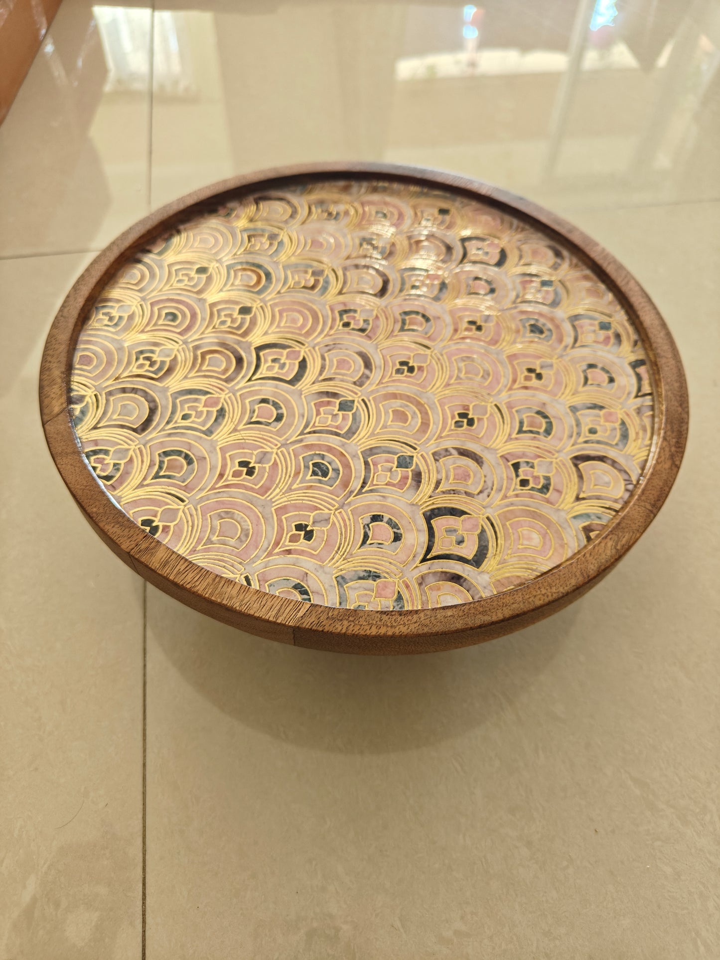 Wooden Cake Stand with a patterned top on a tiled floor