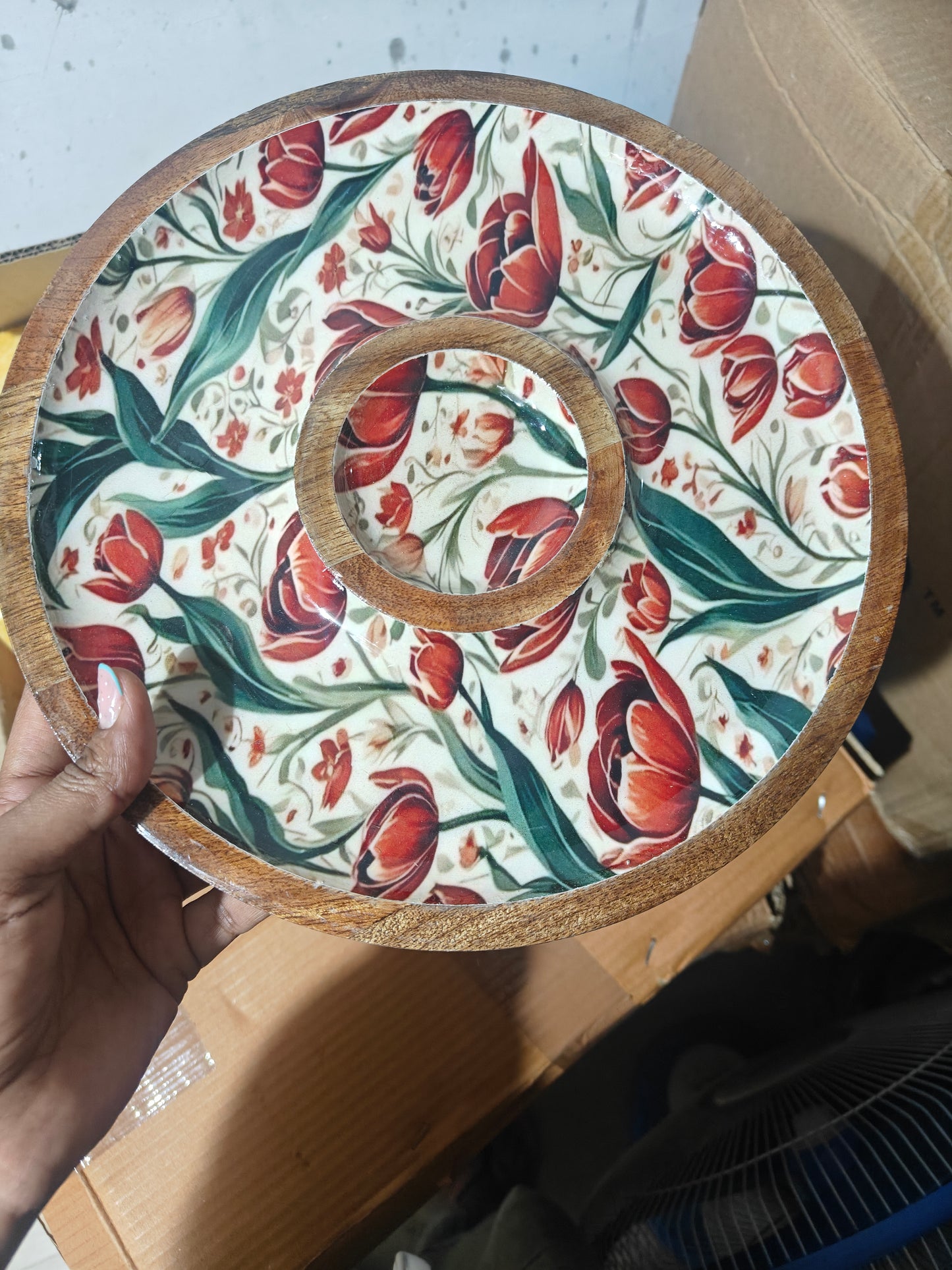 Decorative plate with floral pattern held by a hand on a plain background