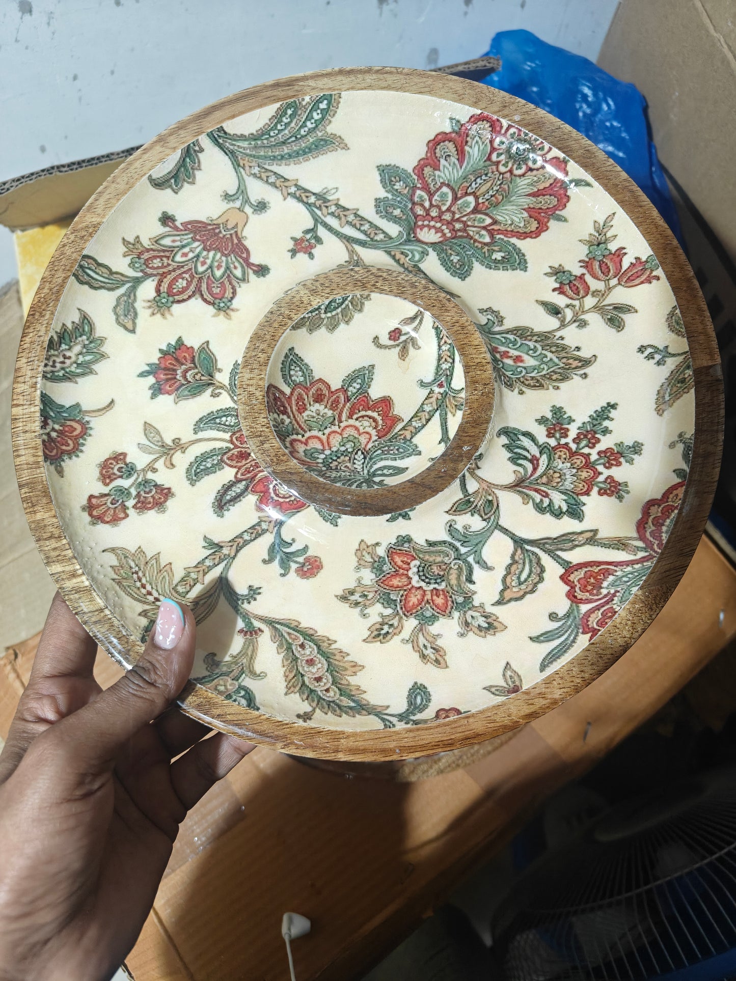 Decorative Wooden Round Chip-n-Dip Platter with Bow with floral pattern held by a hand against a blurred background