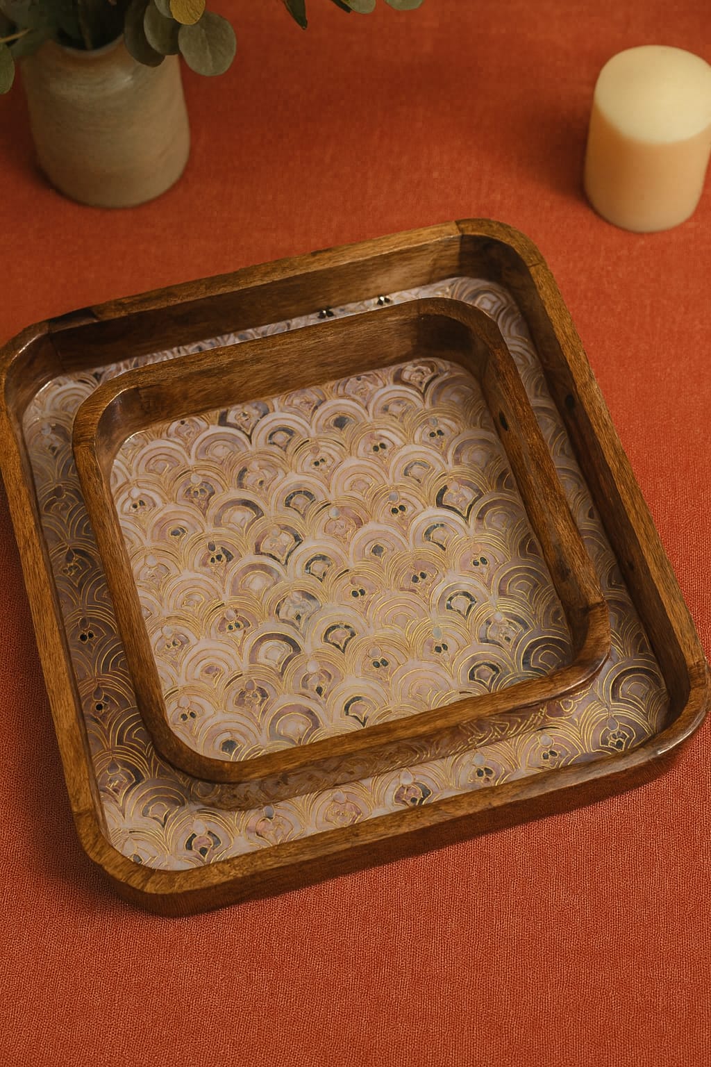 Two wooden trays with patterned linings on a red surface.
